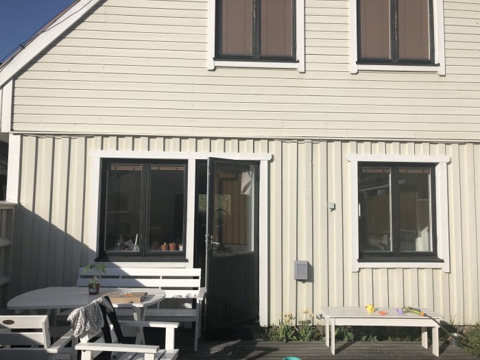 Vit träfasad på ett 1,5-plans hus där användaren överväger att installera en terrassmarkis.