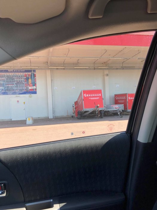 Vy från bilen till en lastkaj vid Bauhaus där en släpvagn med luckan nere står utanför lastområdet.