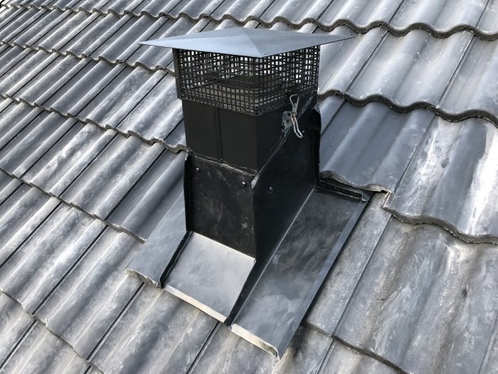 Tak med svart ventilationstrumma och nyinstallerad plåt som ser dåligt utformad och monterad ut.