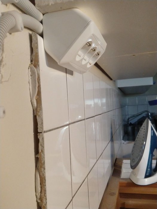 Rivningsarbete av gammalt kakel i kök med synlig vägg och eluttag.