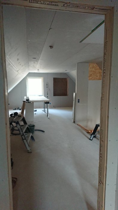 Renoveringsarbete med OSB/plyfa och gips i ett nästan färdigmålat rum med arbetsredskap.