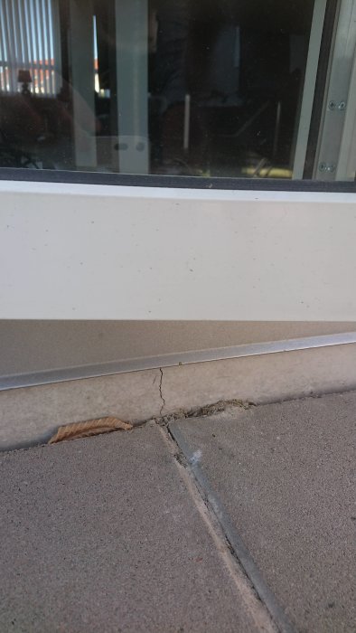 Sprickor i husets yttervägghörn och marksten nära en fönstersockel på ett hus byggt 2014.