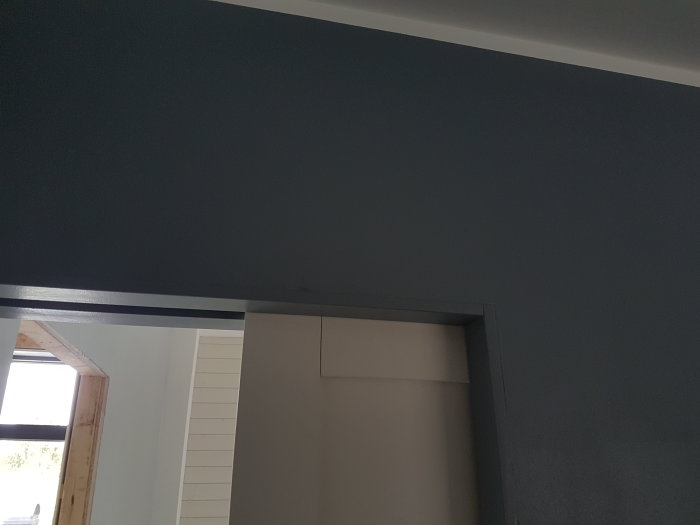 Ojämn fog mellan en MDF-panel och gipstak vid en dörröppning, med synliga springor.