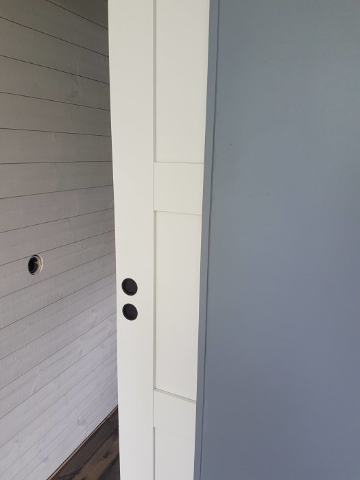 Hörnet där en vit MDF-panel möter en grå gipsskiva med märkbara springor och ojämnheter vid sammanfogningen.