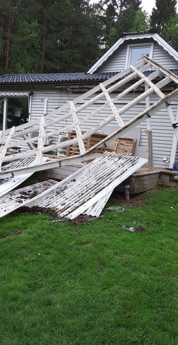 Nedfallna vita plankor och bråte framför ett hus inför en planerad rivning.
