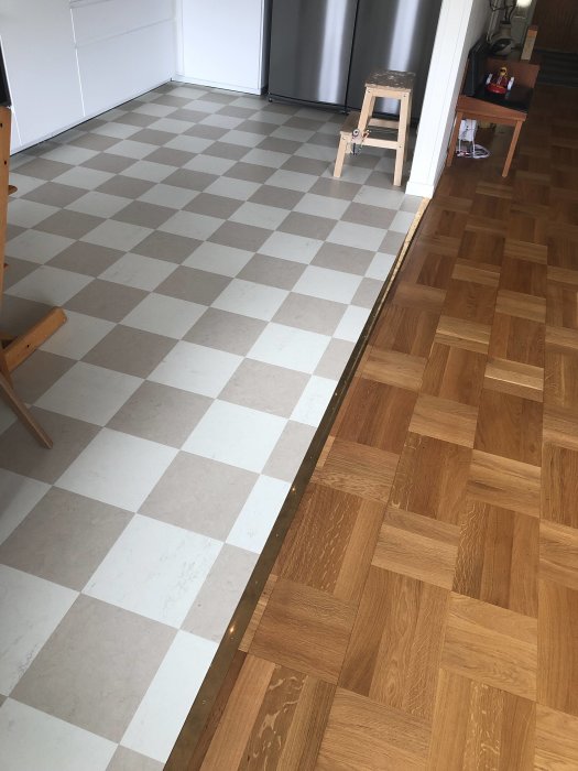 Nyinstallerat schackrutigt golv i vitt och grått möter befintligt träparkettgolv.
