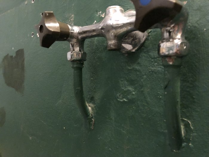 Kromad blandare monterad på grön vägg utan handtag eller anslutna rör.