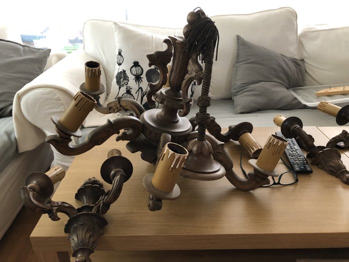 Nedmonterad träkrona och matchande lampetter i gammaldags stil på ett vardagsrumsbord.