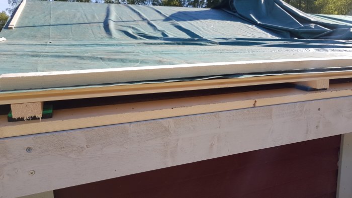 Tak under renovering med ny råspont och luftspalt, täckt med presenning.