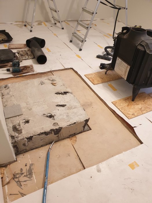 Renoveringsarbete vid braskamin, borttaget klinker och exponerad underlag av gips och spånskiva.