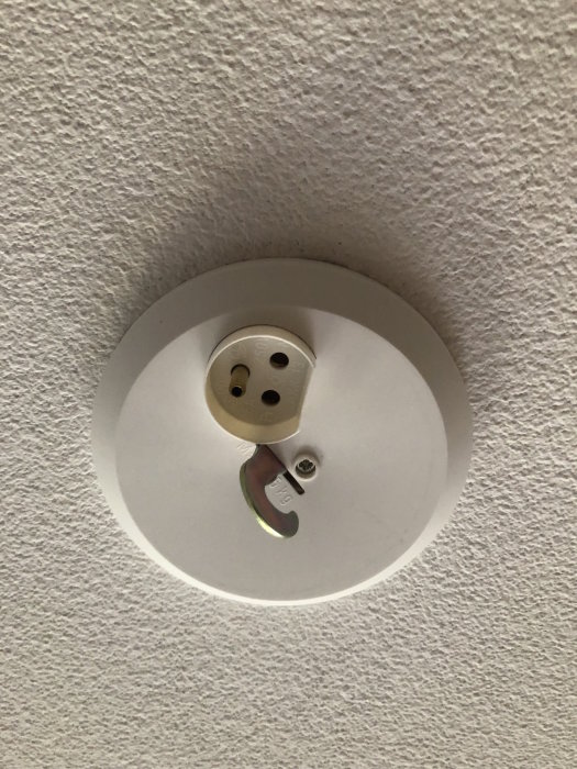 Takuttag utan jordning för lampa, med synlig koppling och skruvfäste mot vit takyta.