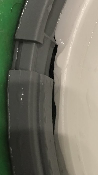 Skada på kanten av en vit golvbrunn med en synlig spricka mot en grå del.