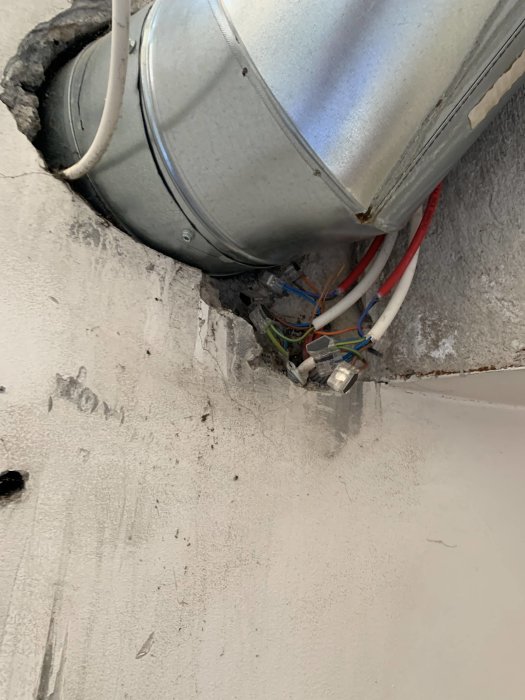 Ventilationsrör och exponerade elektriska kablar i ett hål i väggen på en restaurang.