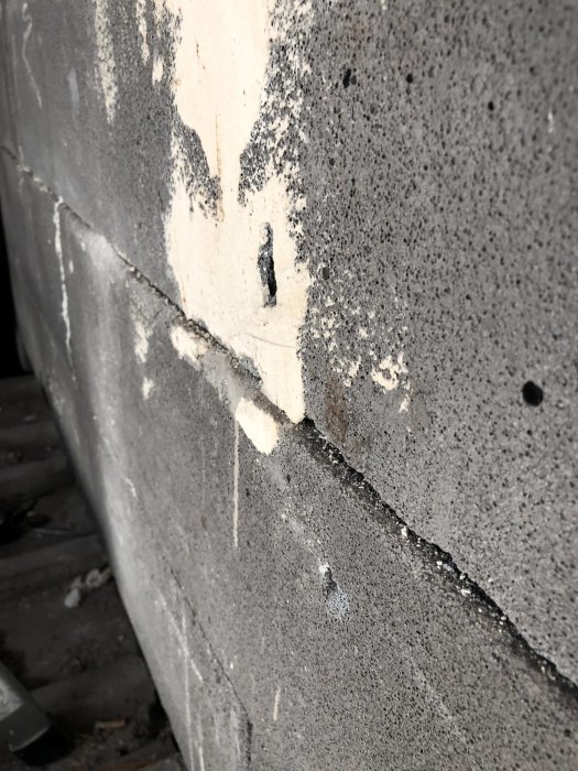 Närbild på en spricka i en yttervägg med gammalt spackel där blocken förskjutits mot varandra.