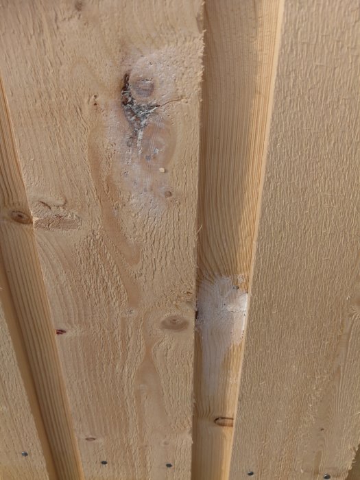 Trävägg med potentiell lim- eller spackelanvändning på fogar mellan träpaneler.
