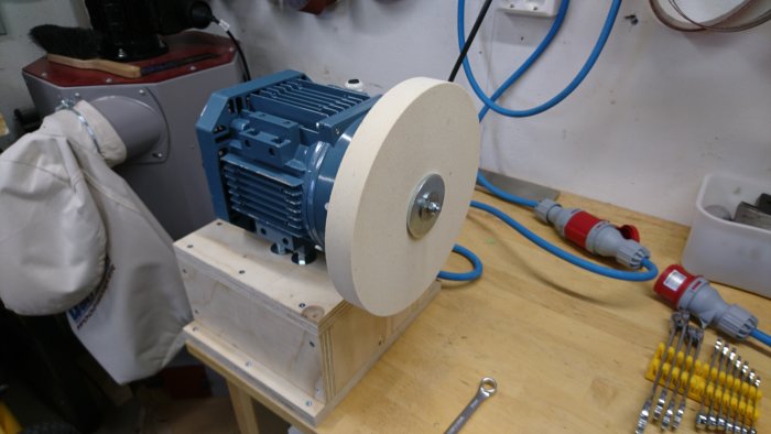 En brynmaskin med en stor filtskiva på en arbetsbänk i en verkstad, redo för diamantspray och ett CBN-hjul.