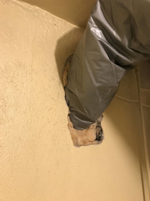 Ej färdigställd genomföring i vägg med byggskum och tejp som täcker öppningen.