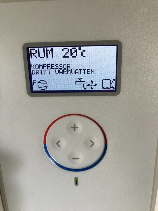 Digital display av värmesystem som visar rumstemperatur och kompressorstatus, omgiven av justeringsknappar.