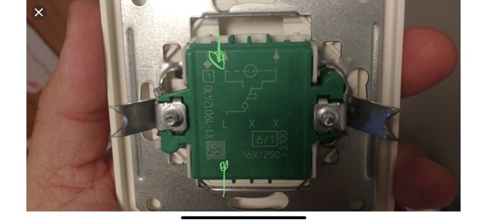 Grön elektrisk dosa med markerade kontaktpunkter för kabelanslutning, monterad på vägg.
