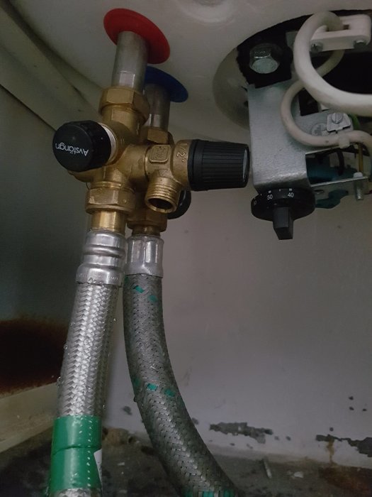 Värmesystem med rör och ventiler under en varmvattenberedare, möjlig luftfickas indikation.
