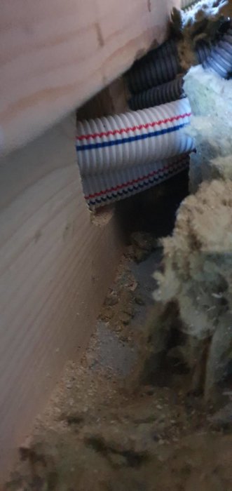 Två närliggande hål i ett bjälklag med genomgående rör för vatteninstallation, relaterat till en byggmiss.