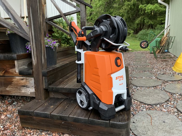 Stihl RE 130 högtryckstvätt med vindsnurra och sladdar, placerad på en trätrappa utomhus.