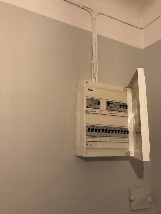 Elskåp på vägg under elkabelrör, vit märkt linje visar önskad ny placering.