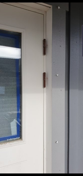 Entrédörr och karm som visar gångjärn och skylt med texten "Gatlingshuset".