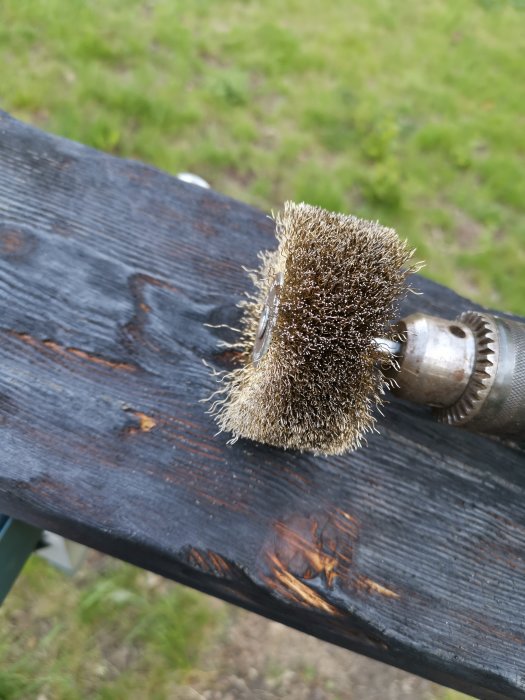 Slipborste på en borrmaskin vidbehandlar ytan av ett mörkbetsat träbord utomhus.