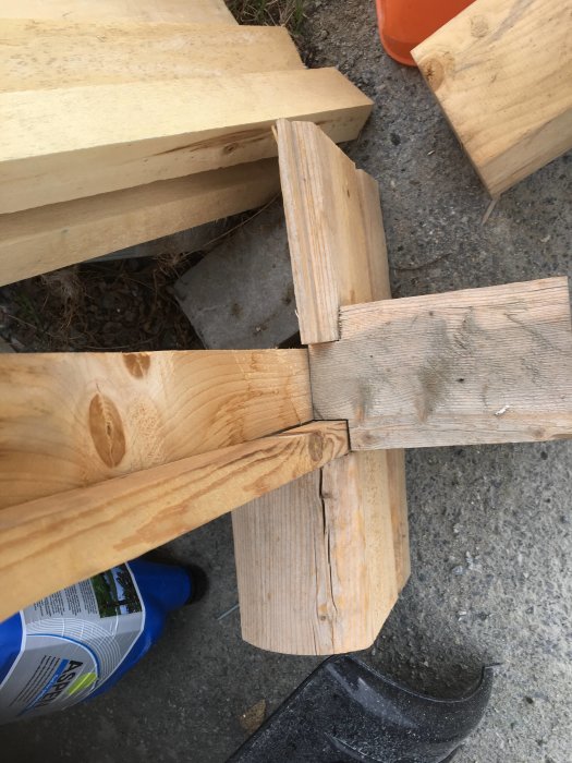 Närbild av timmerpanel och formade knutar under montering mot en betonggrund.