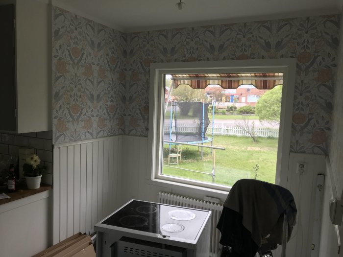 Kökshörna med fönster, spis och ingen installerad belysning, blommigt tapet, förberedd för belysningsråd.