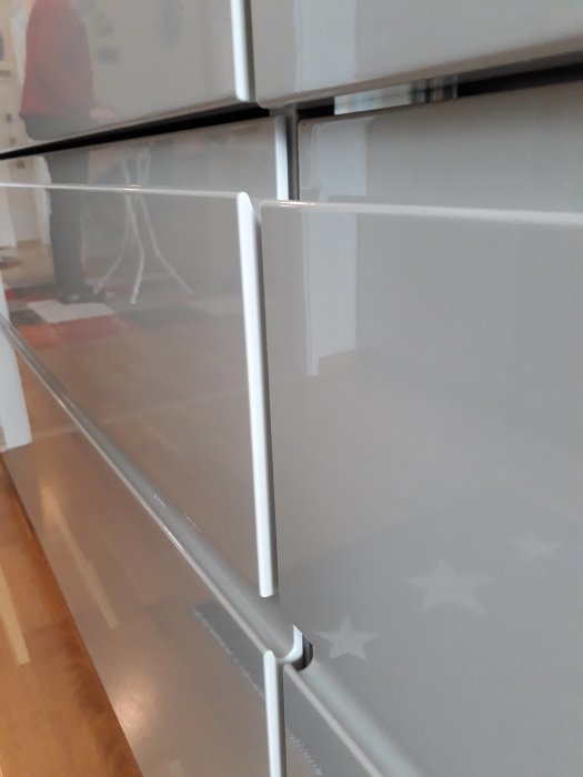 IKEA-skåplucka står ut lite upptill, synligt mellanrum, böjda järn syns på sidan av skåpen.