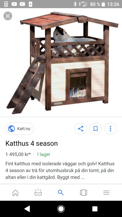 Ett isolerat tvåvåningskatthus med trappa, balkong och en katt som tittar ut.