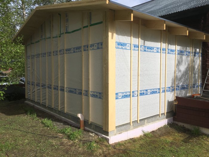 Byggnad under konstruktion med nyinstallerad vindpapp på trästomme.