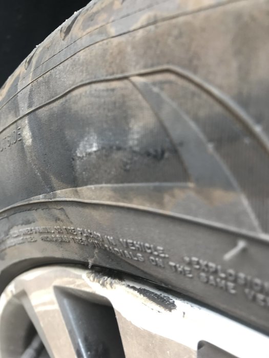 Bilens däck med skador och en utbuktning orsakad av kollision med en trottoarkant.