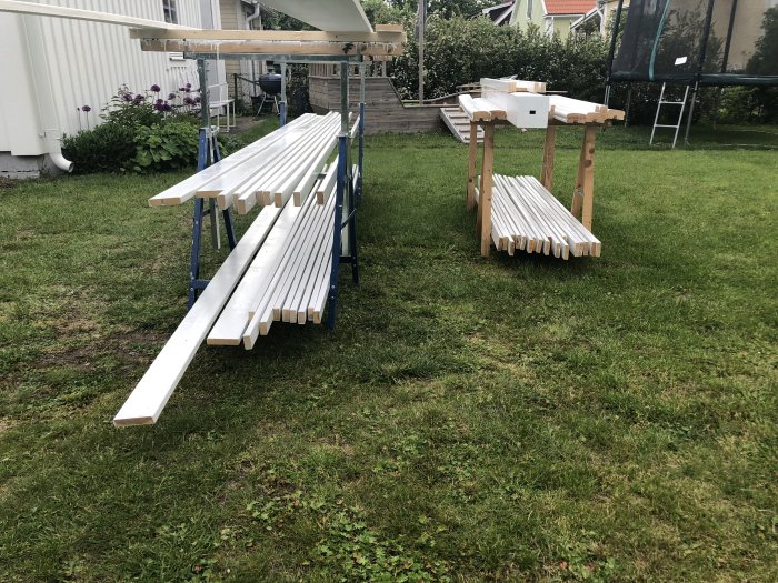 Nymålade vita brädor uppställda på bockar utomhus för torkning.