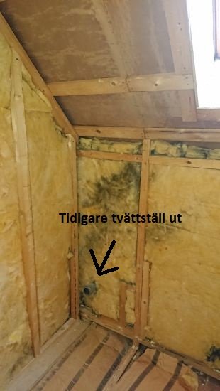 Badrumsrenovering före: öppen vägg med isolering och avloppsrör markerat som tidigare tvättställsutlopp.