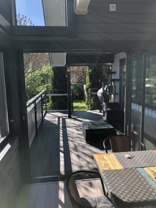 Altan under konstruktion med delvis installerat räcke och uteplatsmöbler på en solig dag.