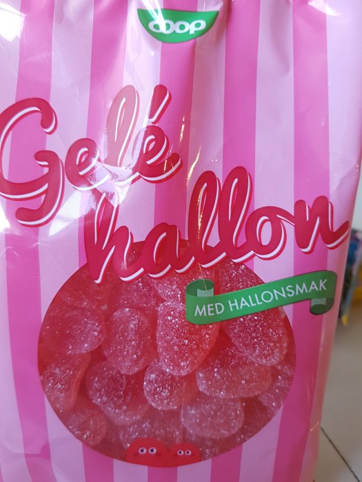 Förpackning av geléhallon med texten "Gelé hallon" och "Med hallonsmak" på rosa randig bakgrund.