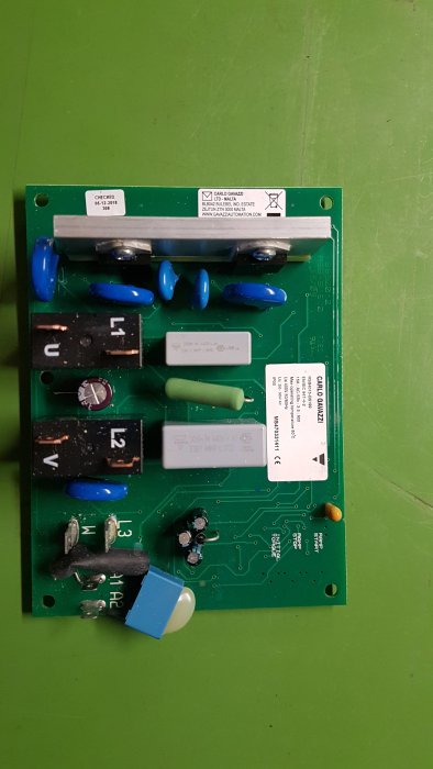 Kretskort med blå kondensatorer och säkringar, märkt med "CARLO GAVAZZI" och kontrollerad den 5 december 2018.