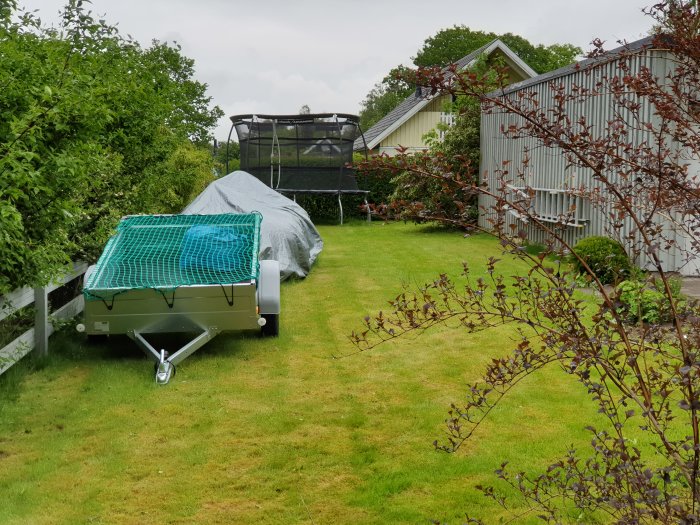 En stor, plan gräsmatta mellan hus och häckar med gångvägar, passande för en robotgräsklippare.