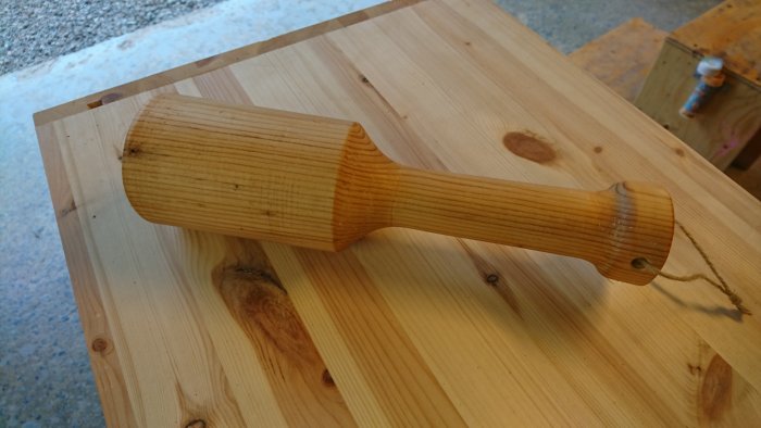 Handgjord träknopp svarvad i trä och behandlad med linoljevax, ligger på ett träbord.