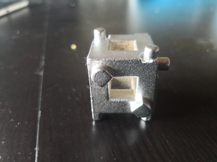 Metallisk maskindel på en mörk yta.