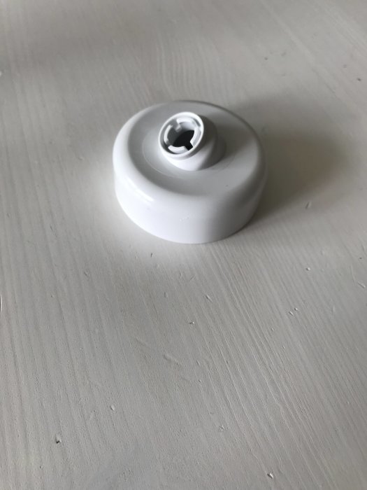 Vit taklamphållare monterad på ljusgrå yta.