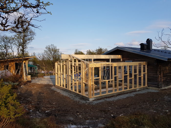 Unfinished wooden house frame construction on a sunny day with clear skies.