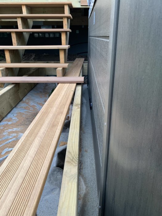 Delvis inbyggt spabad vid en veranda, med synlig betongplatta och trätrall, samt utrymme för luckor.