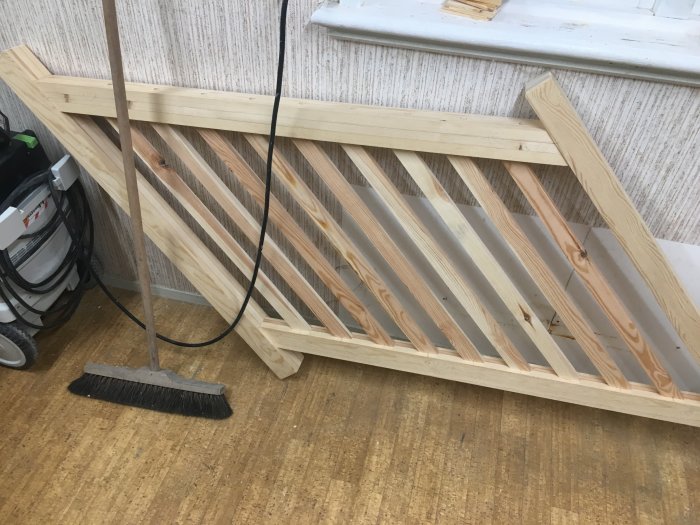 Torrmonterade trästolpar och plankor som utgör ett halvfärdigt trappräcke liggandes på golvet.