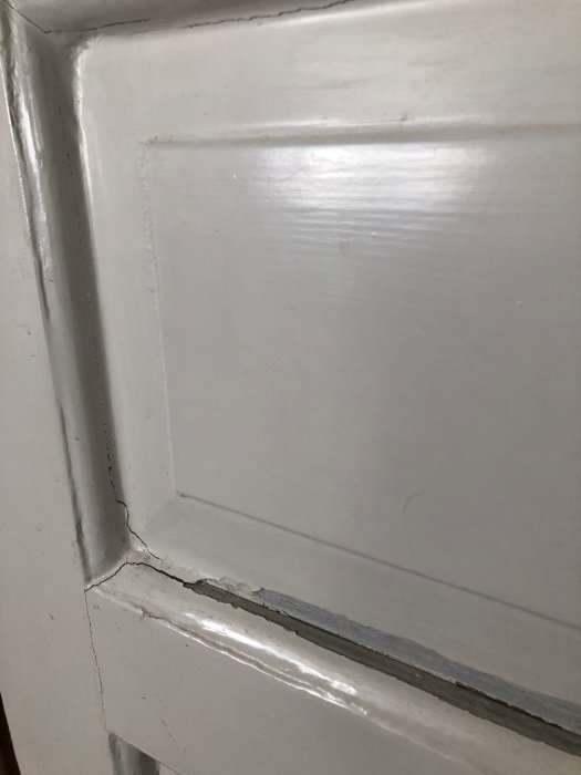 Del av vitmålad dörr och karm skrapad och grundmålad med linoljefärg, redo för renovering.