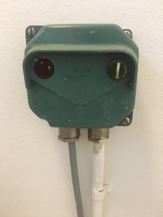 Gammal fast installerad dosa för tvättmaskin med 380V märkning och sladdar.