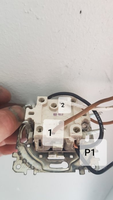 Öppnad gammal dubbelströmbrytare med synlig trådkoppling och etiketterade kontakter i ett garage.